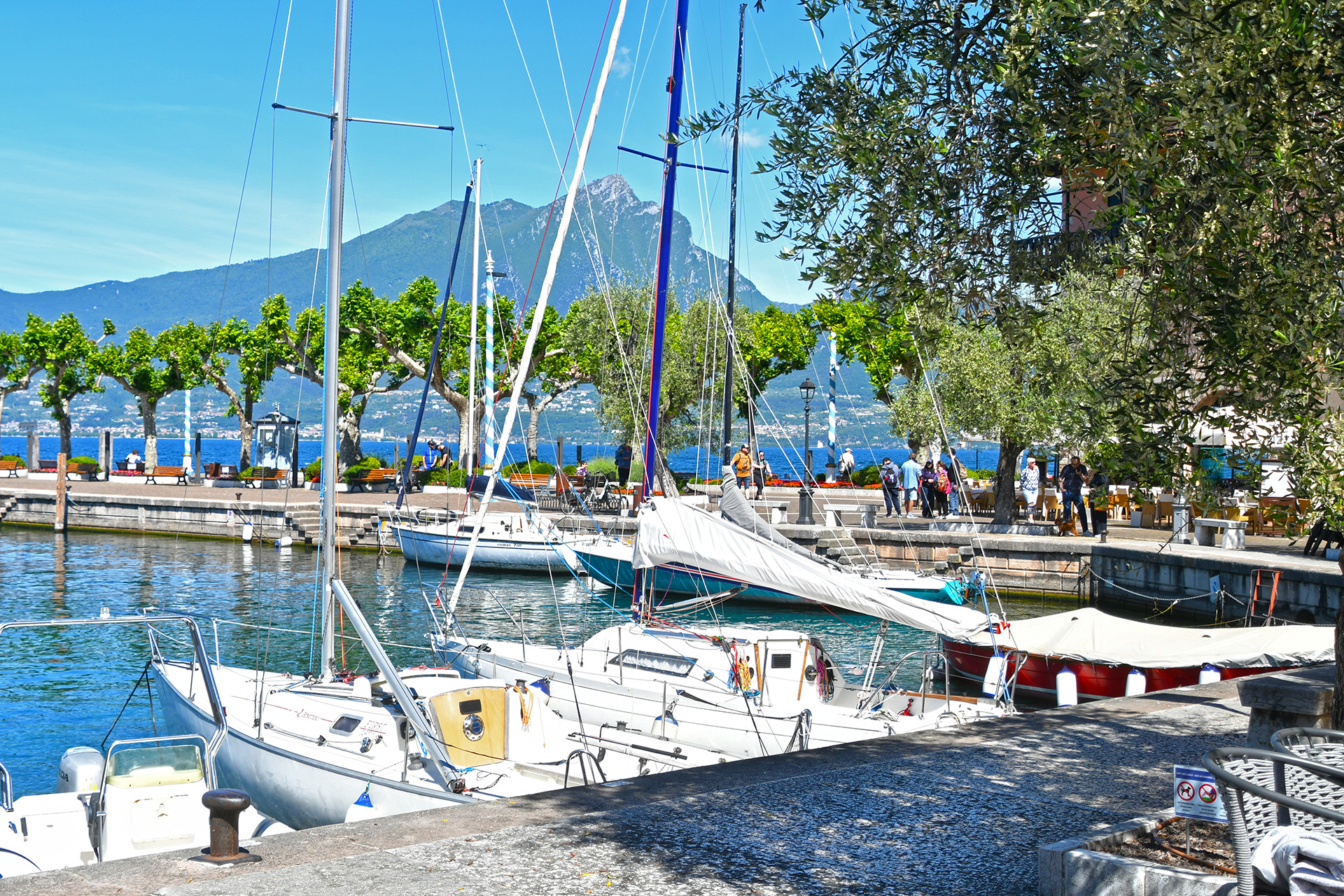 Porto di Torri del Benaco con barche a vela, lago e montagne sullo sfondo