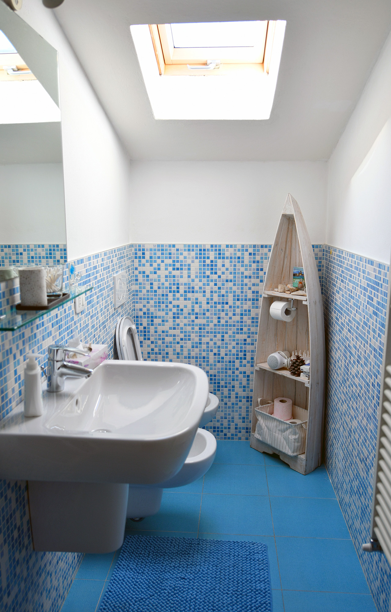 Bagno con mosaico azzurro, velux e dettagli a tema lago