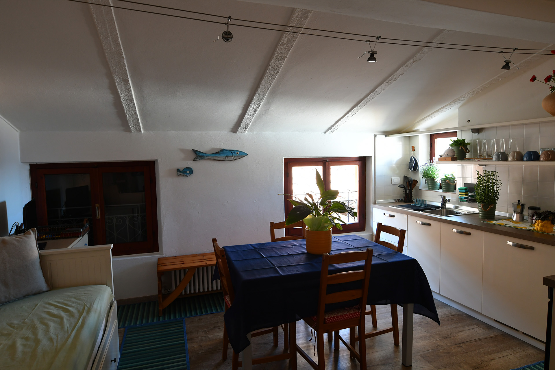 Zona giorno con travi a vista, tavolo da pranzo e cucina attrezzata